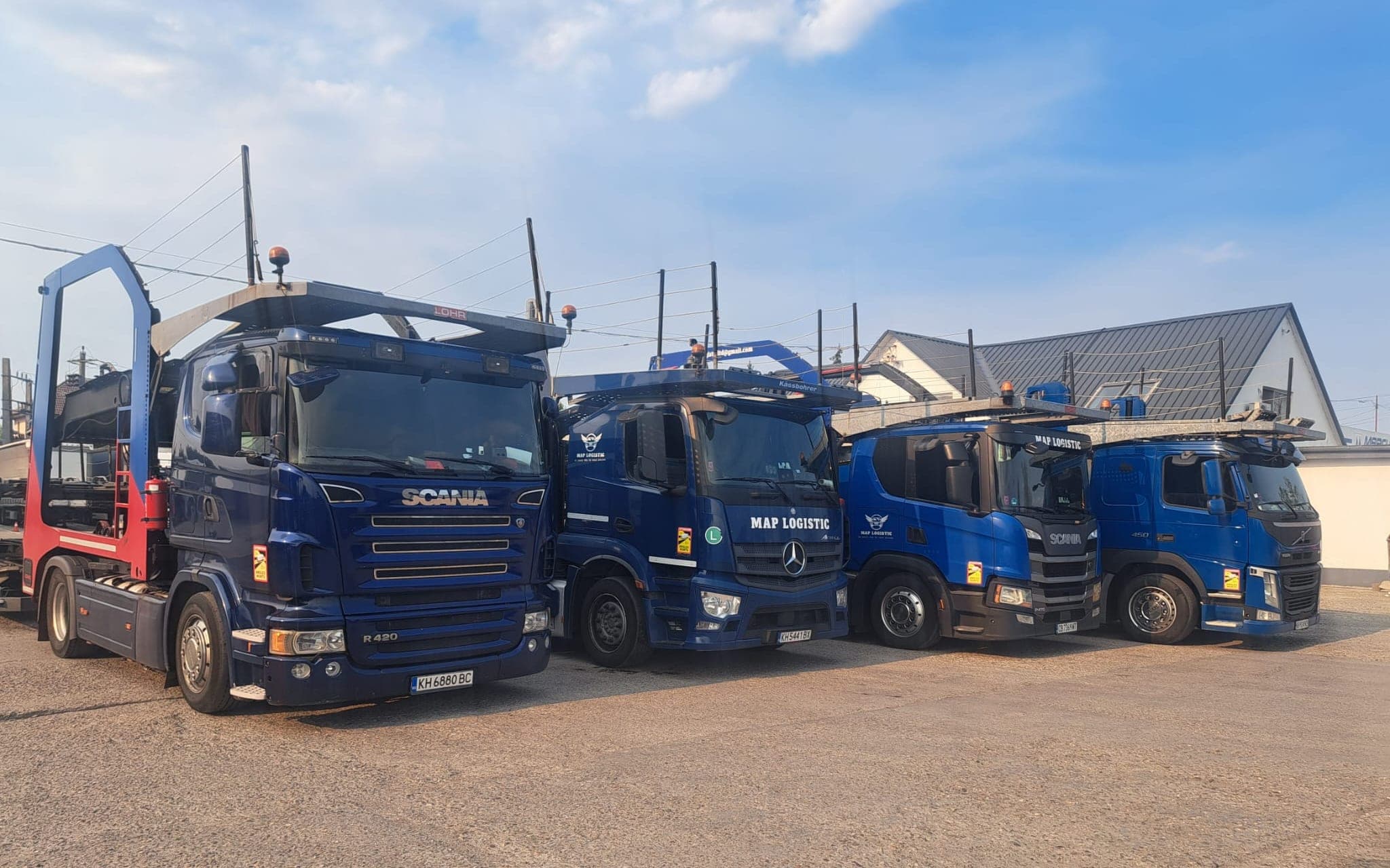 Четири сини автовоза на MAP LOGISTIC, паркирани един до друг, снимани под ъгъл