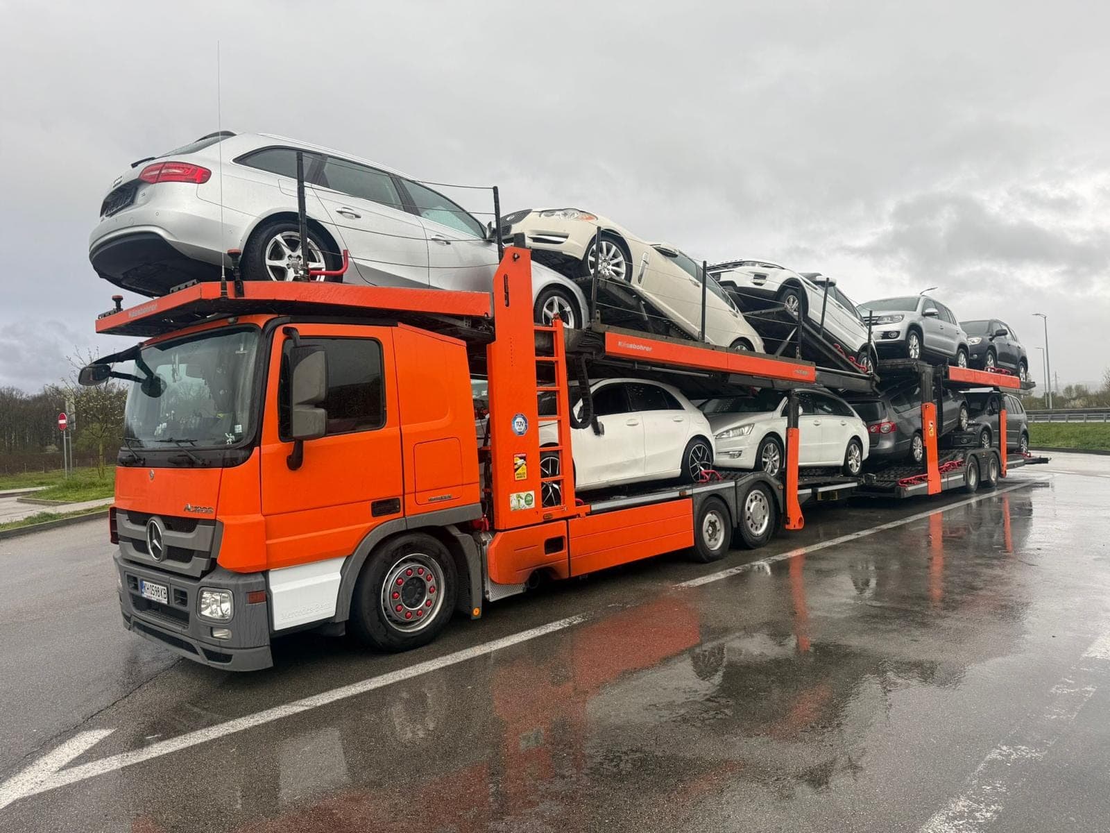 Нашият оранжев автовоз Mercedes-Benz Actros, натоварен с употребявани коли в дъждовен ден