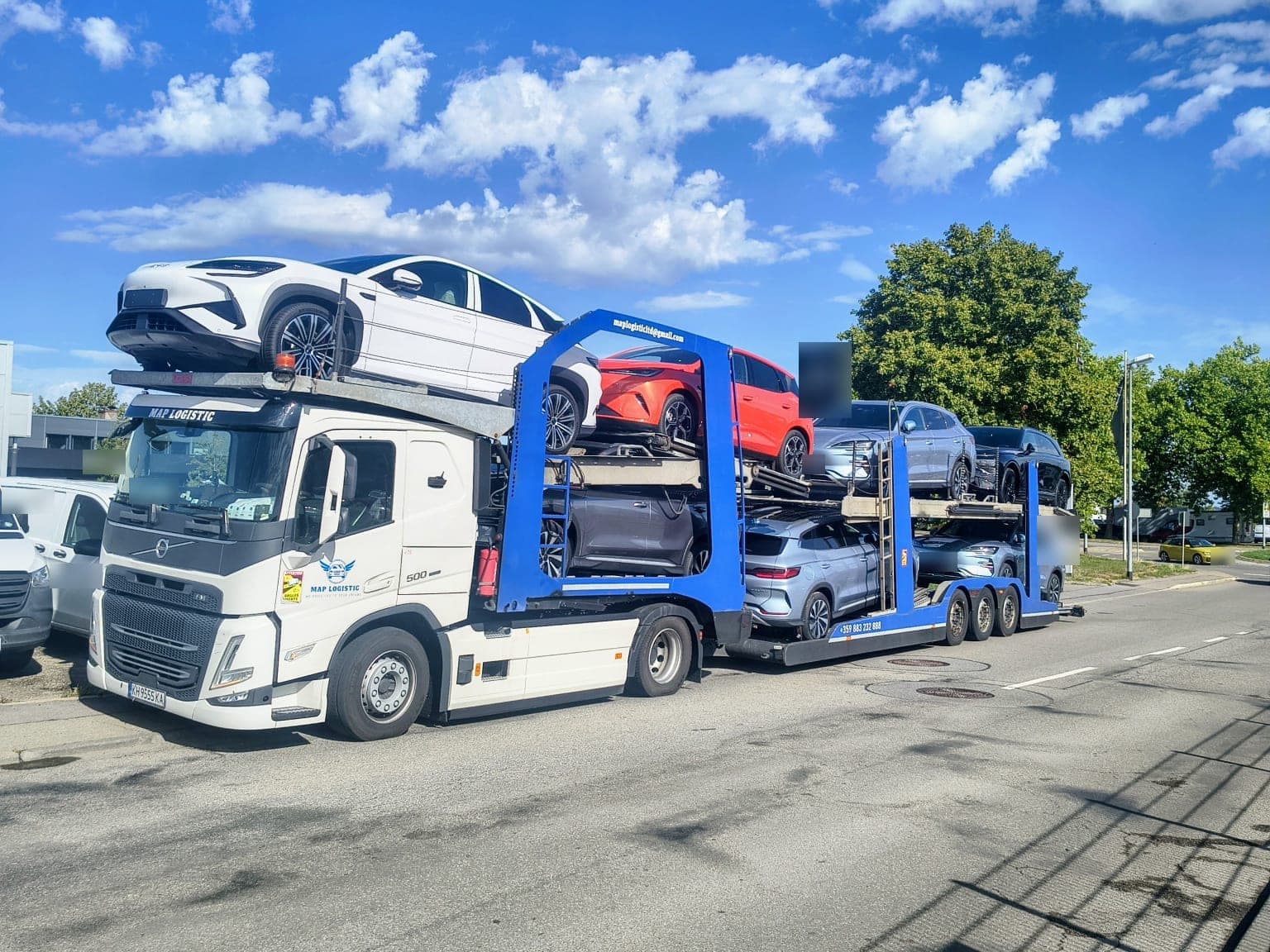Нашият бял автовоз Volvo, натоварен с нови джипове под синьо небе